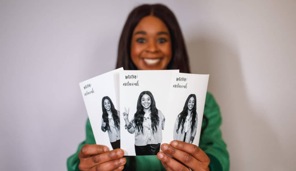 A guest at a corporate event having fun showing printouts of photos she had taken in black and white