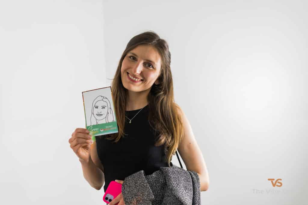 A lady at a party showing the copy of her face, drawn by the Sketch Bot