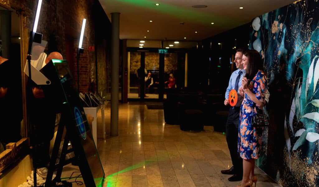 A couple of guests using props and posing for photos in front of the Mirror Air