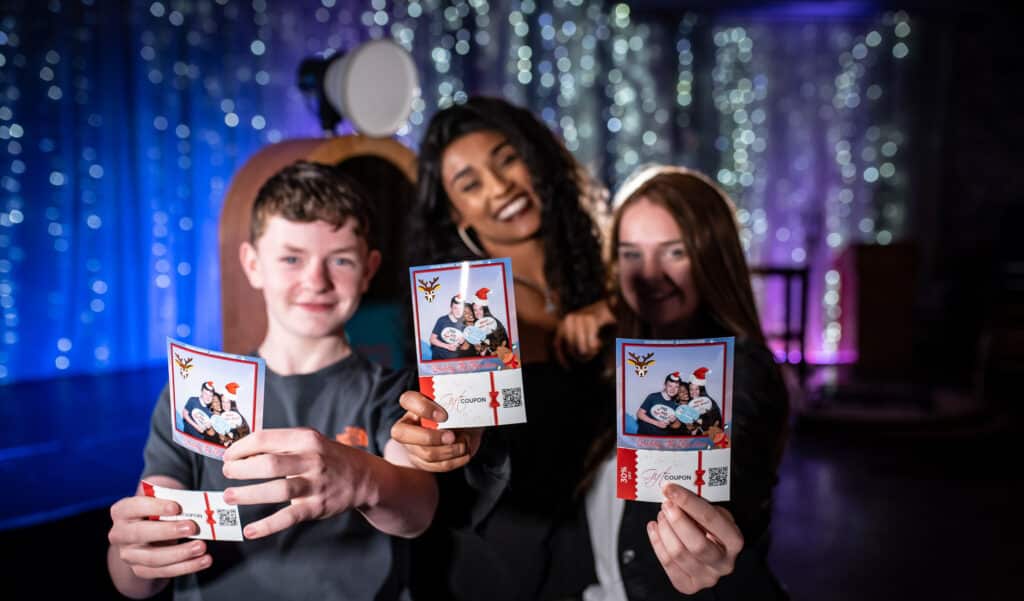 3 young people holding their Christmas selfies printed on 4x6 paper
