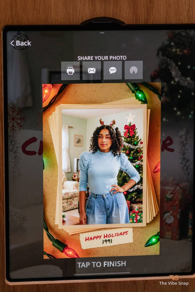 A young woman in a blue top and a man in a reindeer sweater posing against a snowy blue background, transformed into a 1991 holiday scene using a photo booth app, part of the AI Nostalgic Holiday experience
