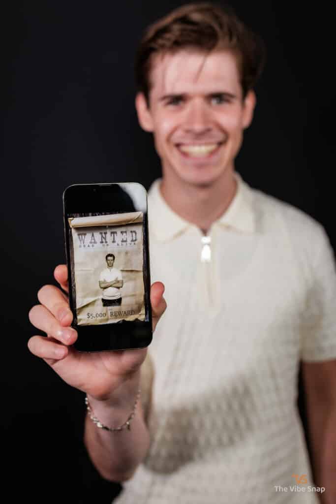 The Wild West Experience - A young man holding an iphone with wanted poster