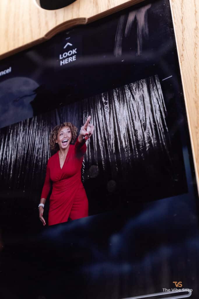 Mixed race lady in red dress on the photo booth screen while recording Santa sleigh ride experience