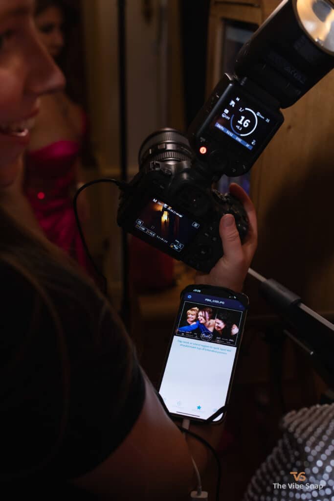 Young female photographer holding a professional camera showing guest their most recent photo