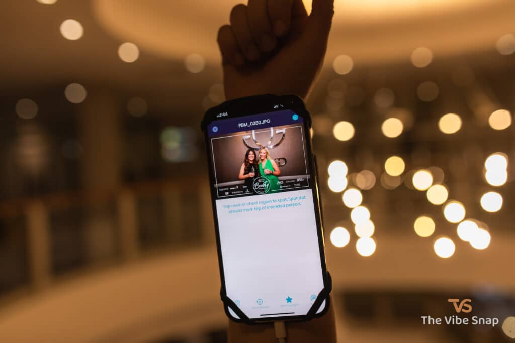 Photo of two ladies on an iPhone attached to the arm of an event photographer