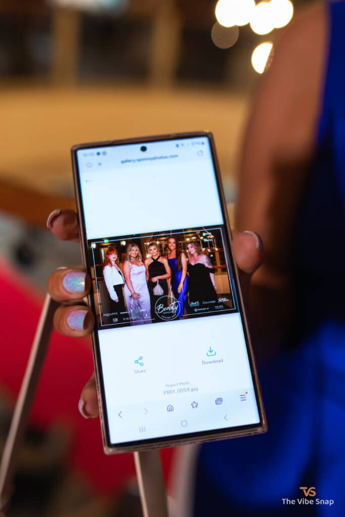 Lady holding a phone with a photo of 5 guests from the Beauty Excellence Award